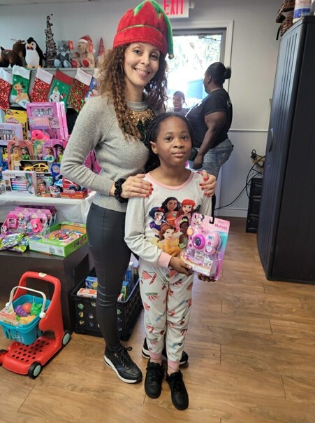 A woman smiling with a kid holding a toy for a picture.