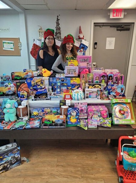 Two women stand behind a table full of gifts.